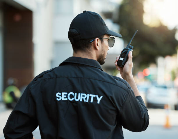 istockphoto-1618446911-612x612 Radio, man and a security guard or safety officer outdoor on a city road for communication. Back of a person with a walkie talkie on urban street to report crime for investigation and surveillance